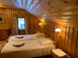 1 dormitorio con 2 camas en una habitación con paredes de madera en Hôtel Restaurant Eden en Evolène