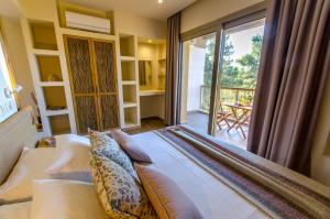 a bedroom with a large bed and a balcony at Forest Resort Suites Skiathos in Troulos