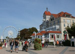 a group of people walking around a city with a ferris wheel at Meeresblick in Kühlungsborn