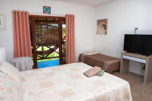 a room with a bed and a tv and a window at Recanto dos Dendês Chalés in Serra Grande