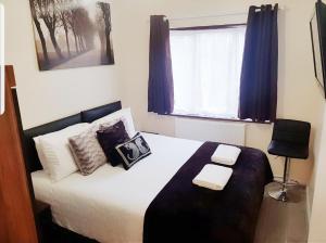 um quarto com uma cama com almofadas e uma janela em The 55 em Enfield