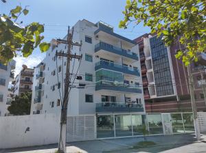 a white building with blue balconies and a tree at APARTAMENTO PARA 10 pessoas CABO FRIO in Cabo Frio