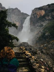 una mujer sentada en las escaleras frente a una cascada en Theasis-Igloo en Ágnanta