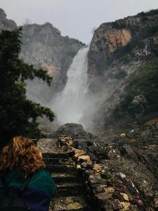 a woman sitting on steps in front of a waterfall at Theasis-Igloo in Ágnanta