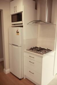 a white kitchen with a stove top oven next to a refrigerator at Apartment on St Georges in Havelock North