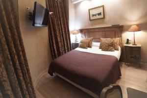 a hotel room with a bed and a flat screen tv at Hôtel du Château in Vincennes