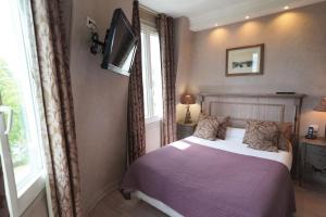 um quarto com uma cama, uma televisão e uma janela em Hôtel du Château em Vincennes