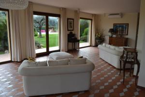 Una sala de estar con dos sofás blancos y un piano. en Villa Zagara Luxury Bed And Breakfast, en Pescara