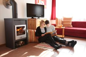 Ein Mann und eine Frau sitzen in einem Wohnzimmer mit einem Buch in der Unterkunft Hütte Präbichl in Vordernberg