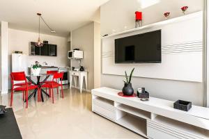 sala de estar con TV y mesa con sillas rojas en Apto Jurerê Open Shopping c/ churrasqueira CDS106, en Florianópolis