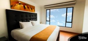 Apartasuites Plaza Modelia في بوغوتا: غرفة نوم بسرير كبير مع نافذة كبيرة