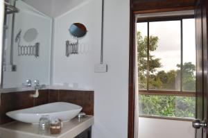 baño con lavabo, espejo y ventana en Aromarte Finca Hotel, en Filandia