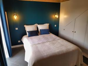 ein Schlafzimmer mit einem Bett mit zwei blauen Kissen in der Unterkunft Le Temps de Vivre in Plouescat
