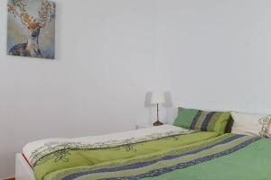 a bedroom with a bed with green sheets and a painting at Shopping street Gewandhaus Netflx Badew. 58zolltv in Leipzig