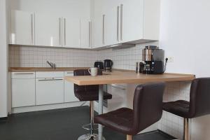 a kitchen with white cabinets and a wooden table with chairs at Shopping street Gewandhaus Netflx Badew. 58zolltv in Leipzig