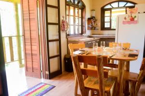 a kitchen with a table with chairs and a refrigerator at Chalé vista da mata in Visconde De Maua
