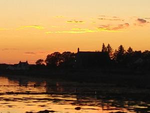 un coucher de soleil sur une étendue d'eau avec un bâtiment dans l'établissement Cartmel, à Aultbea