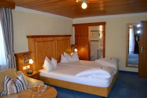a bedroom with a large white bed and a table at Hotel Alpenresi in Ramsau