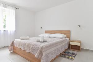- une chambre blanche avec un lit et deux oreillers dans l'établissement Sandy beach apartments, à Ljubač