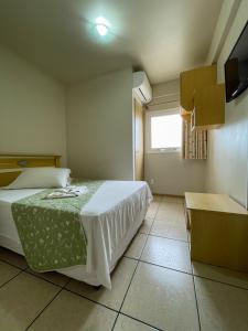 1 dormitorio con 1 cama, TV y ventana en Andardac Hotel, en Guaramirim