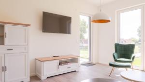 ein Wohnzimmer mit einem TV und einem grünen Stuhl in der Unterkunft Apartmenthaus Wittsande Wittsande 09 in Zingst