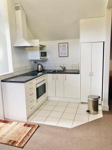 a kitchen with white cabinets and a black counter top at Spacious, Peaceful, Fully Equipped 1BR Apartment in Upper Hutt