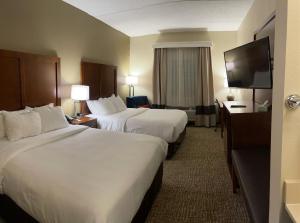 a hotel room with two beds and a flat screen tv at Wingate by Wyndham Pittsburgh West Mifflin in West Mifflin