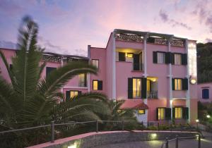 un bâtiment rose avec des palmiers devant lui dans l'établissement Fortuna Beach - Seaside Hotel, à Ischia