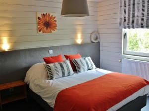 ロンドゥーにあるSpacious Holiday Home in Rendeux with Saunaのベッドルーム1室(オレンジと白の枕が備わるベッド1台付)