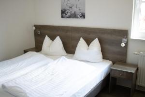 um quarto com uma cama com lençóis brancos e almofadas em Appartement Resort Winterberg - Neuastenbergerstrasse 39-41 em Winterberg