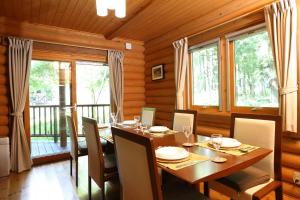 a dining room with a table and chairs and windows at Big Bear Chalets & Apartments in Hakuba
