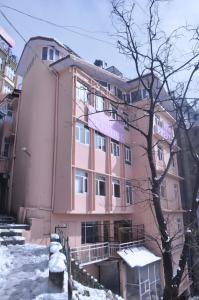 a pink building with snow in front of it at Hotel Prestige in Shimla