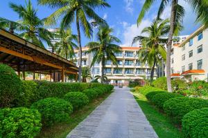 a walkway in front of a building with palm trees at Sanya South China Hotel in Sanya