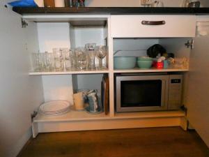 a kitchen with a microwave and some dishes on shelves at Studio Hugo in Nijmegen