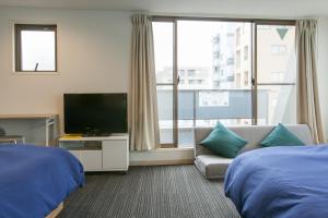 a hotel room with two beds and a flat screen tv at Hotel Cocoro Inn Asakusa Kuramae in Tokyo