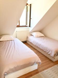 two beds in a attic bedroom with a window at Le 61 bis in Saint-Valery-sur-Somme