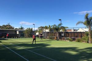 2 persone che giocano a tennis su un campo da tennis di Anglesea Riverside Motel a Anglesea