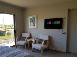 een slaapkamer met 2 stoelen en een tv aan de muur bij Rotorua Views B&B/Apartment in Rotorua