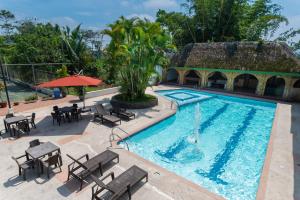 a swimming pool with tables and chairs next to a building at Hotel Zaracay in Santo Domingo de los Colorados