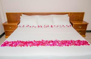 a bed with pink flowers on it at Caribbean Inn and Suites in Saint Johnʼs