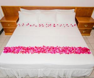 a white bed with pink flowers on it at Caribbean Inn and Suites in Saint Johnʼs