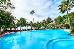 a large swimming pool with palm trees in the background at Hoang Ngoc Beach Resort in Mui Ne