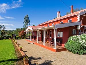 a red house with a patio and a yard at Teanest Nightingale by Nature Resorts in Kotagiri