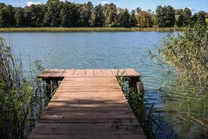 a wooden dock in the middle of a lake at Domki Nad Jeziorem "Półwysep SURYTY" in Suryty