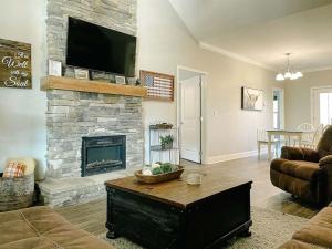 a living room with a stone fireplace with a flat screen tv at Smokies Sanctuary with Mountain Views and Resort Perks in Townsend