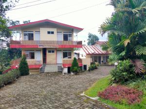a house with a balcony and a driveway at Hotel Anita Baturaden Mitra RedDoorz in Baturaden