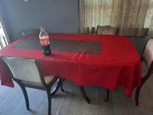 a bottle of soda sitting on a red table with chairs at Bayfair Backpack House in Tauranga