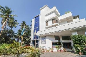 a white building with palm trees in front of it at Fort Gate Hotels & Resorts in Trichūr