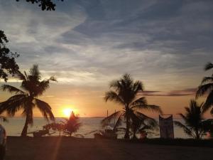 a sunset on a beach with palm trees and the ocean at ARAMARA Resort in Panglao