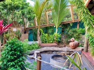 un jardin avec des palmiers et une terrasse en bois dans l'établissement Le Repaire du Dodo, à La Saline Les hauts 